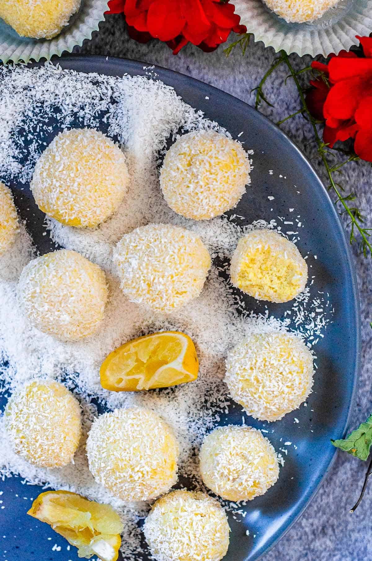 a bunch of cheesecake balls  getting rolled in coconut on a plate