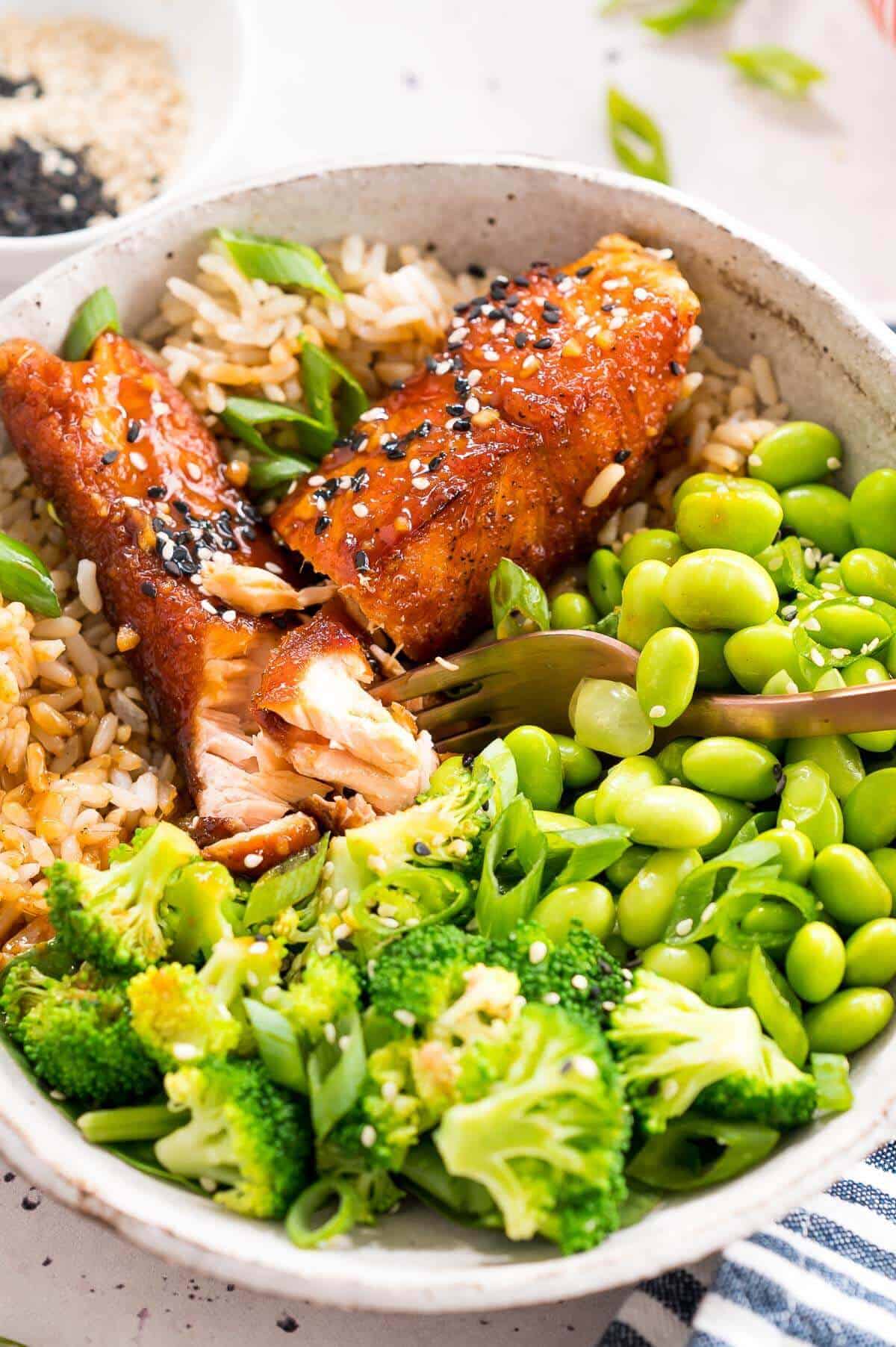 digging into teriyaki salmon bowl with a fork
