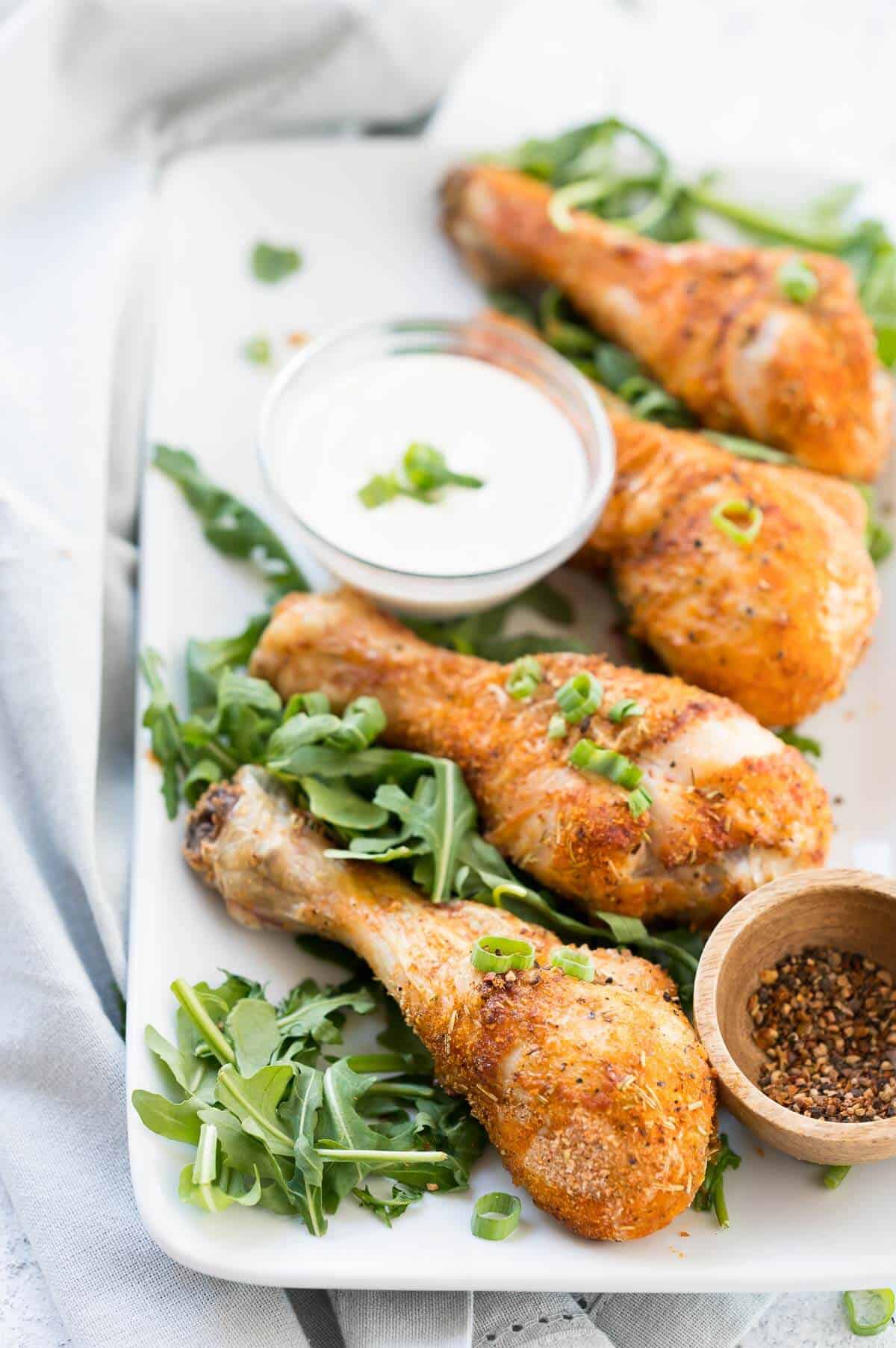 chicken drumsticks on a serving platter with dipping sauce