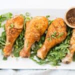 golden air fried chicken legs on a platter of salad greens