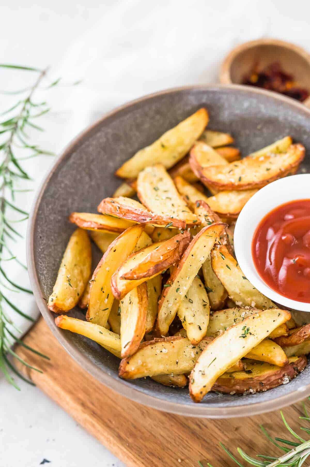 a bowl of potato wedges with a small bowl of sauce on the sauce