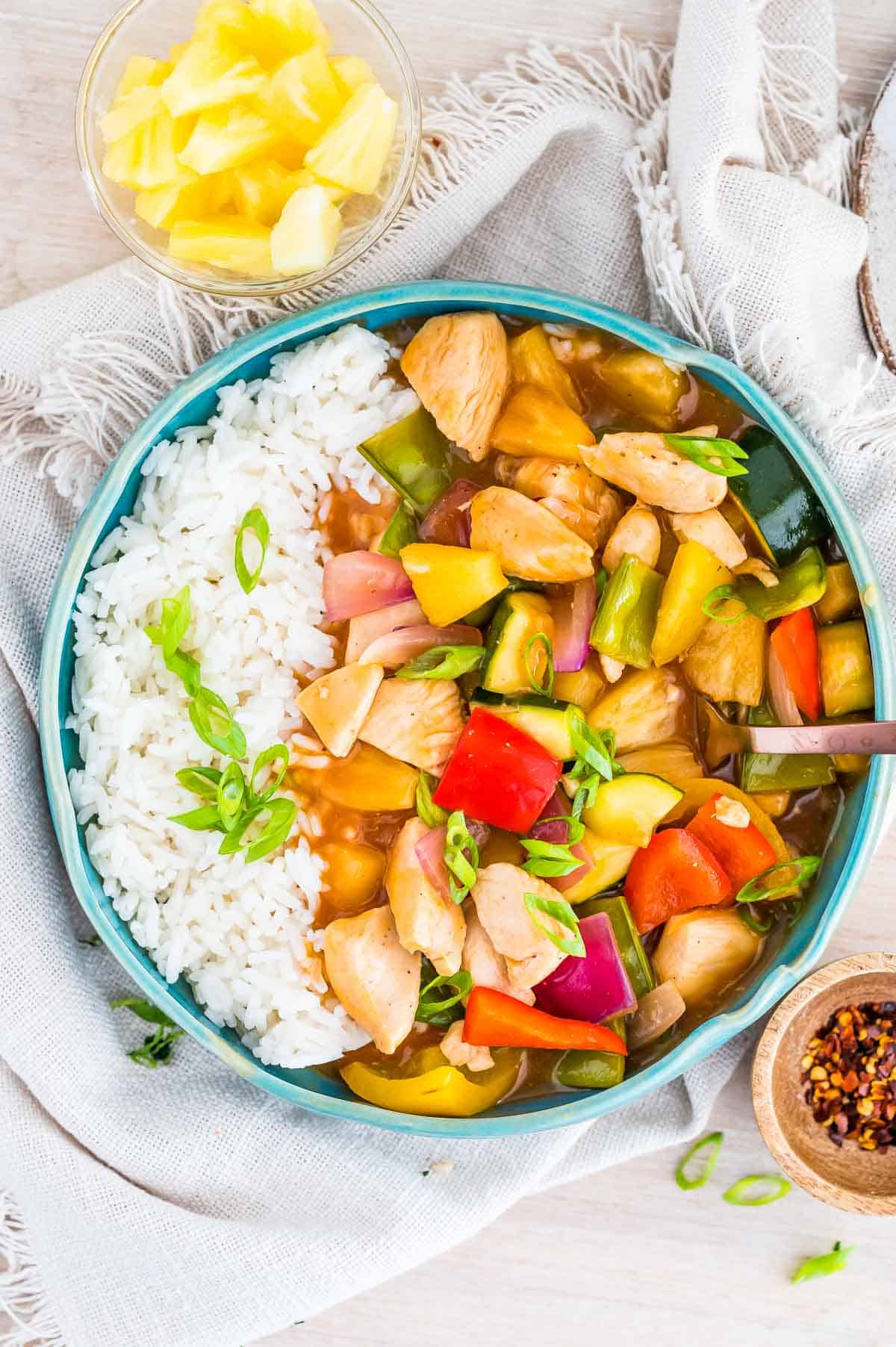 sweet and sour chicken with rice in a bowl with extra pineapple and chilli