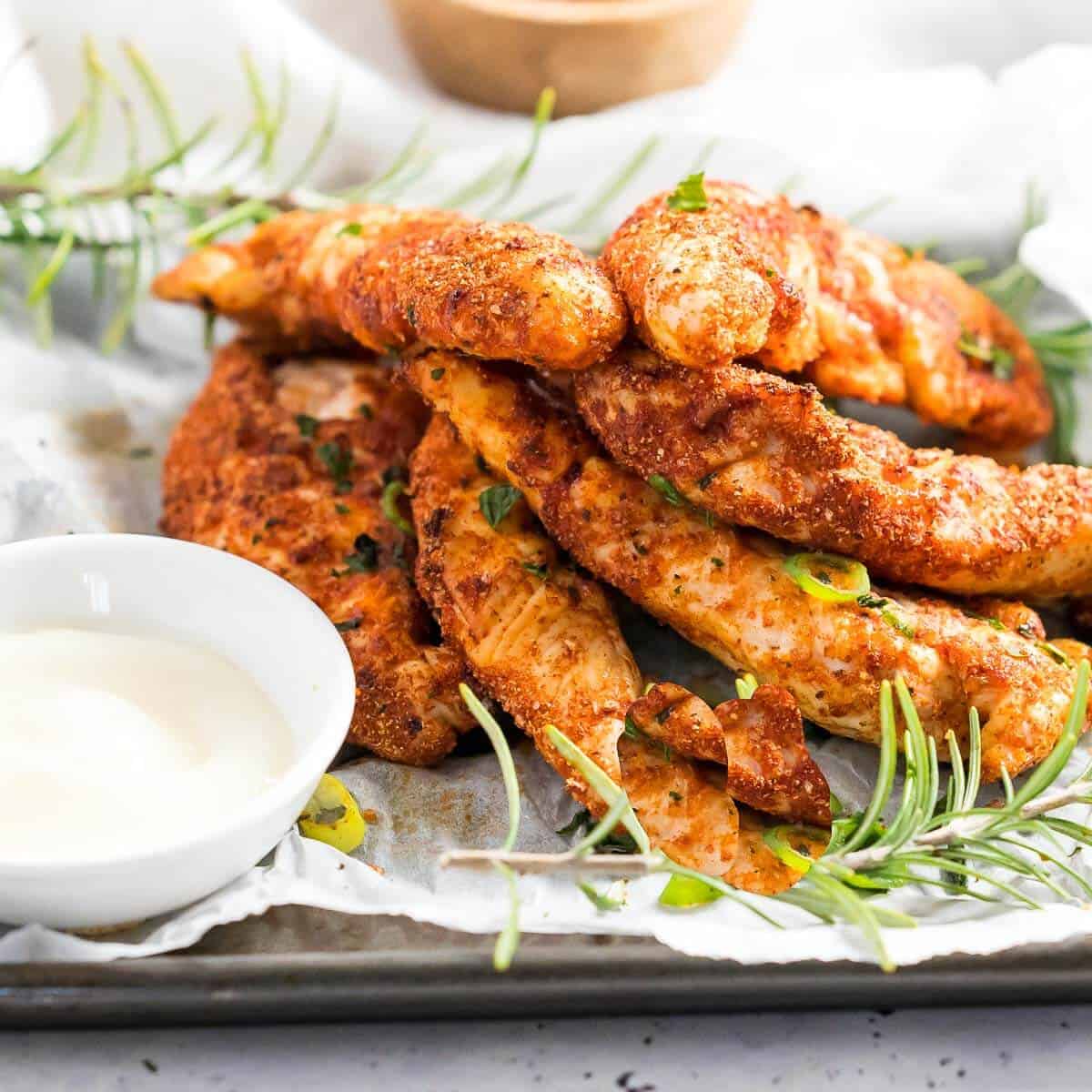 a stack of 6 chicken tenders on a plate with dipping sauce