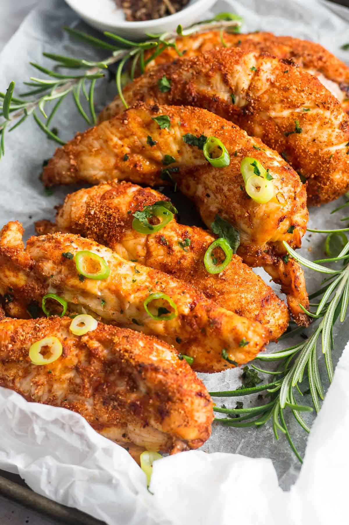 a tray with cooked chicken tenderloins garnished with green onions