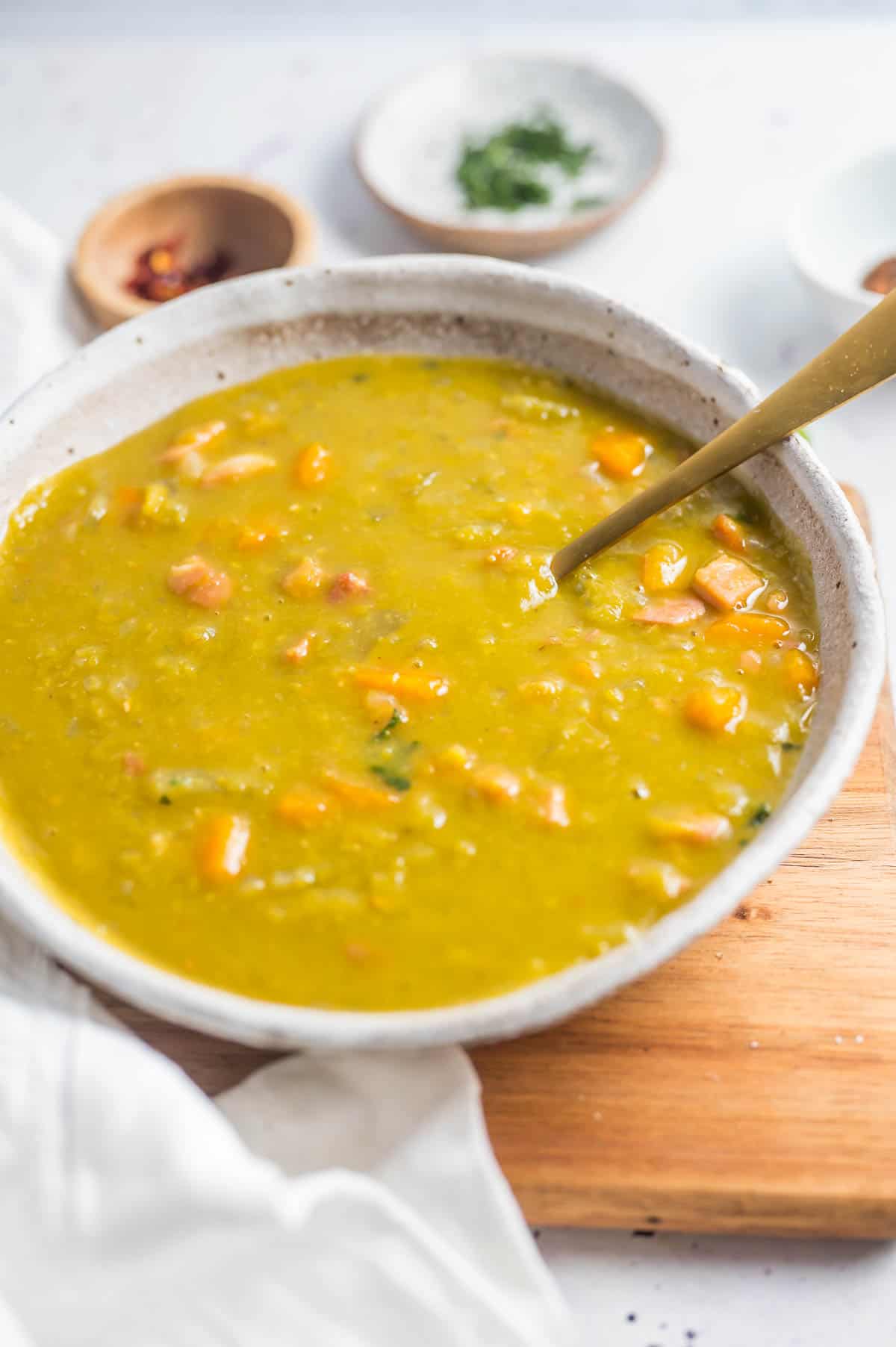 a bowl of pea and bacon soup with spoon in