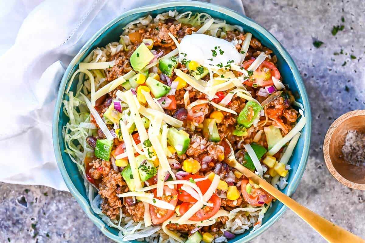 A beef burrito bowl with salsa and grated cheese on top