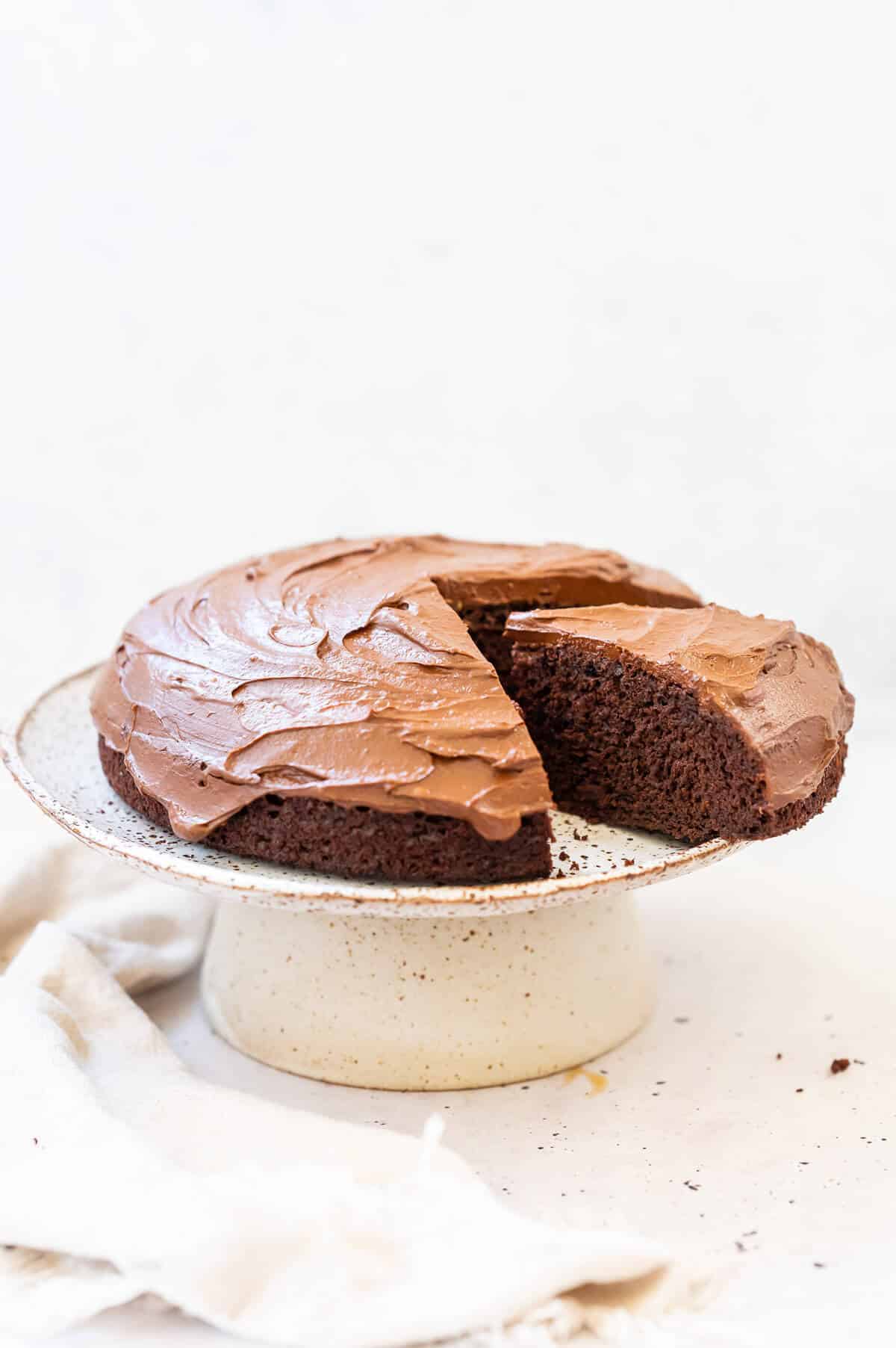 chocolate orange cake on a cake stand with a slice out