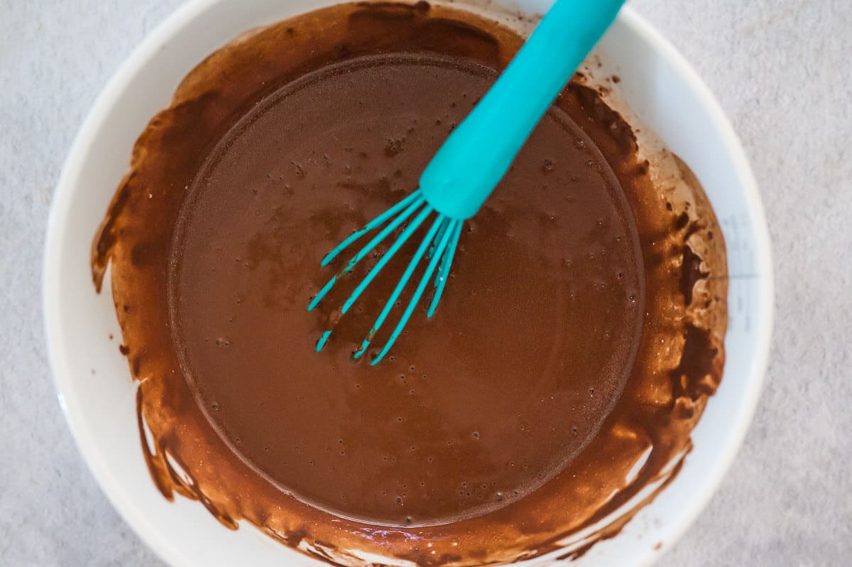 chocolate orange cake batter in a bowl with a blue whisk