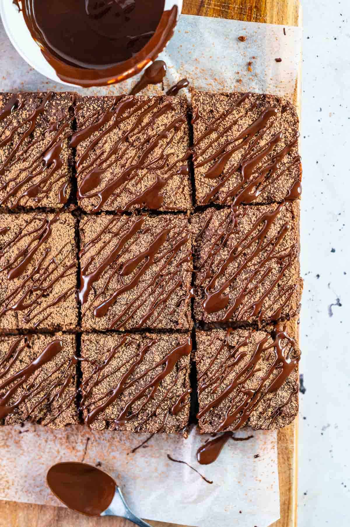 nine brownies on a board drizzled with chocolate