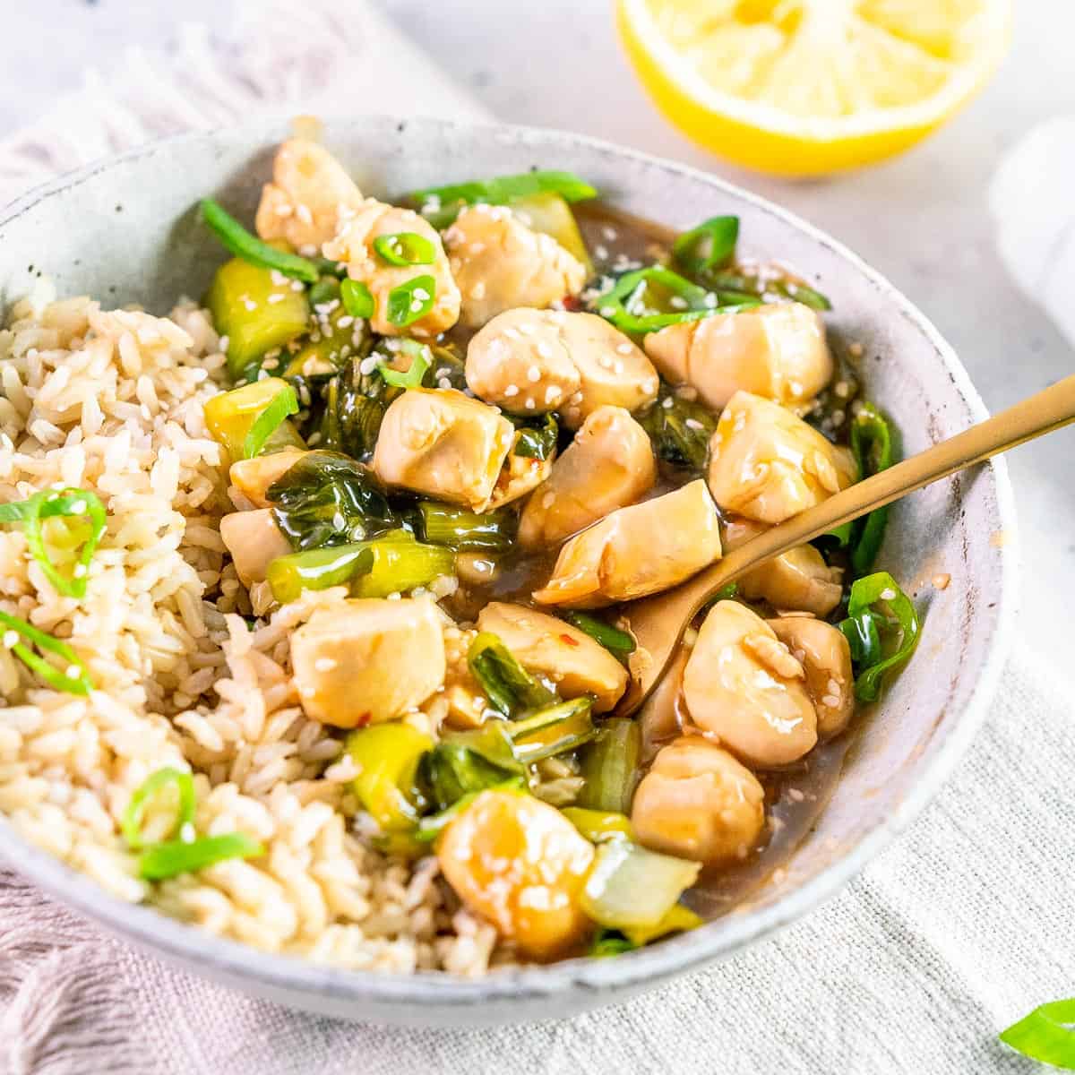 a bowl of lemon chicken with a fork in