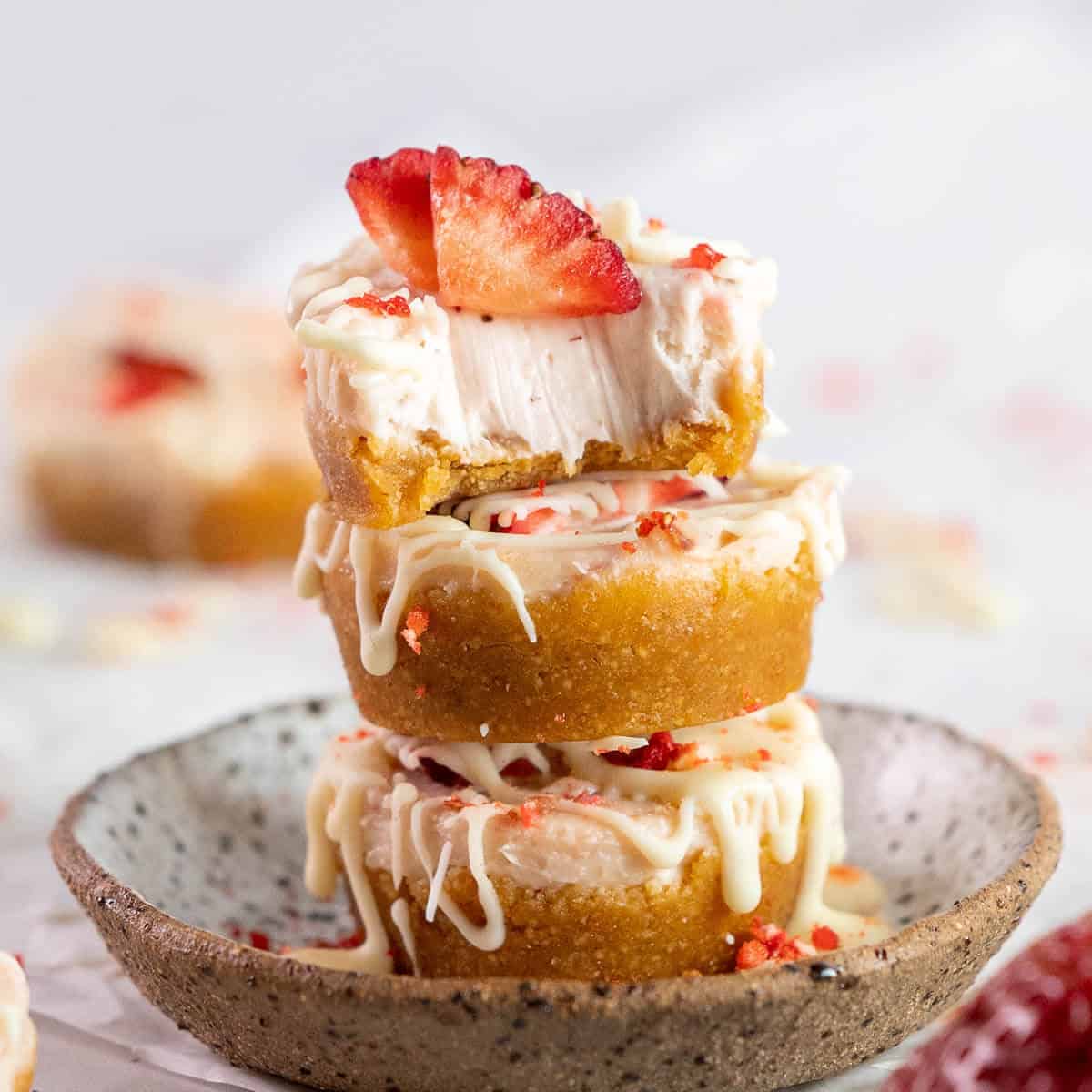 mini strawberry cheesecakes stacked and bite taken out of top one