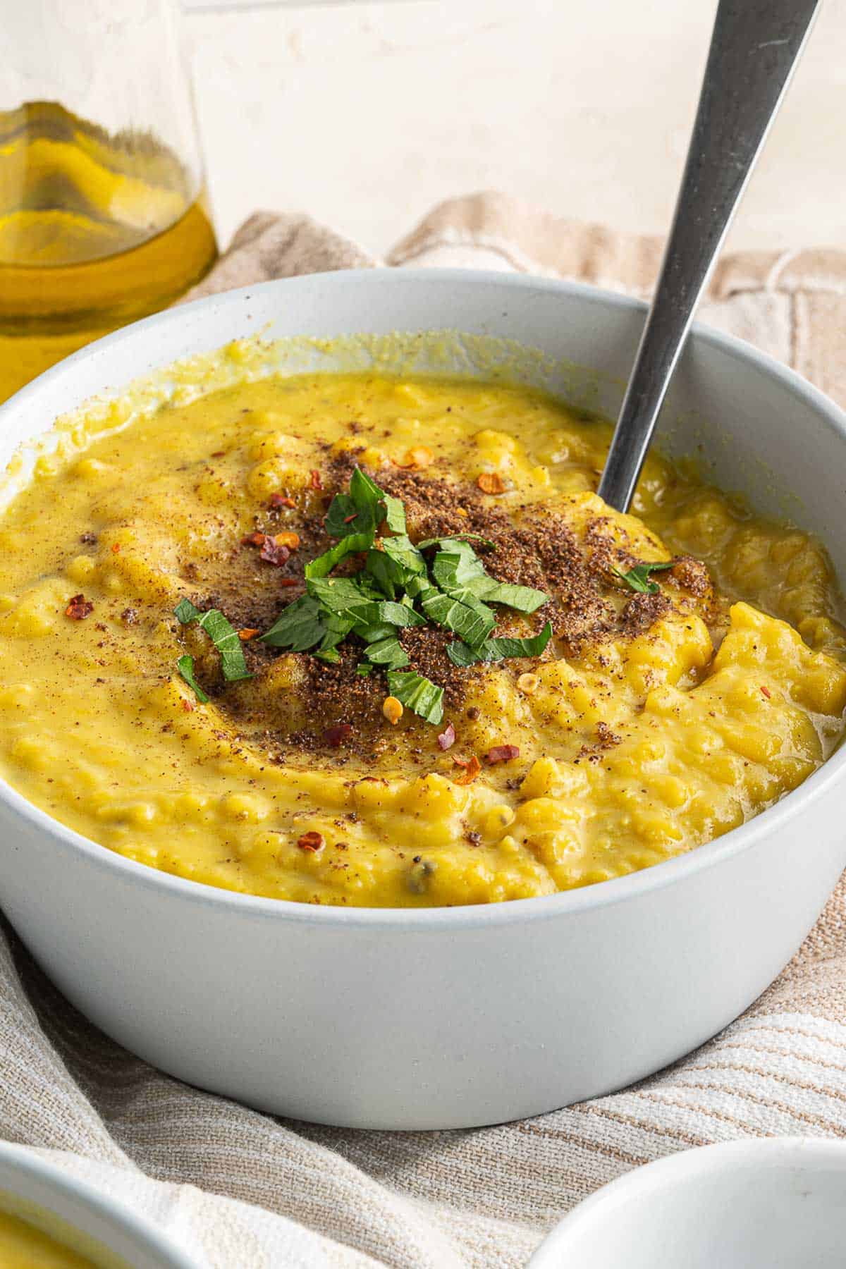 Yellow lentil soup in a bowl with spices and garnish