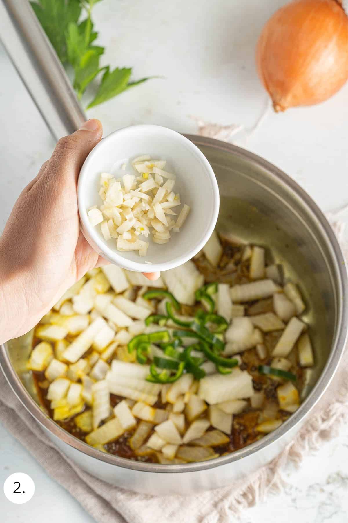 pouring in chopped garlic to pot