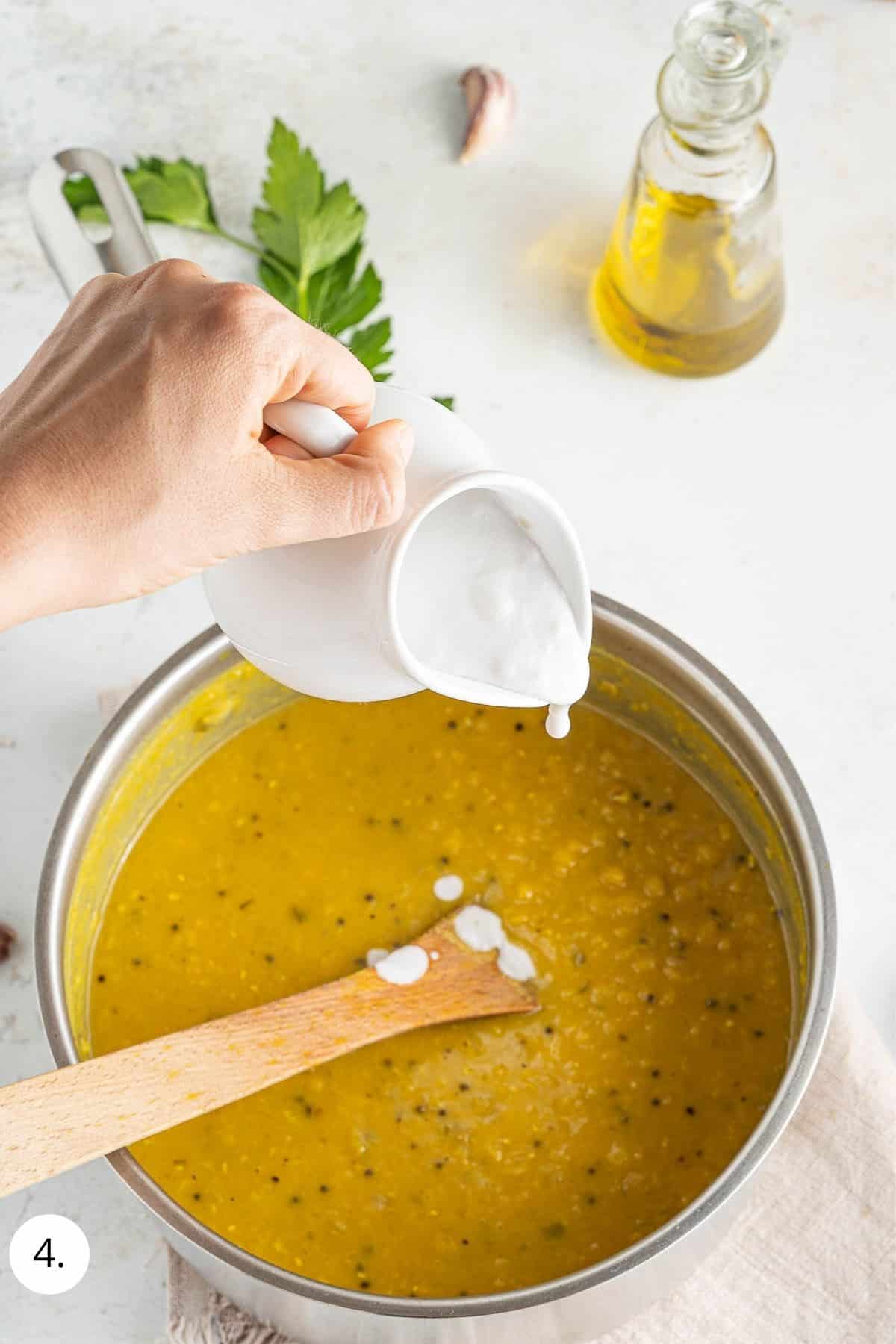 pouring in coconut milk to lentil soup pot