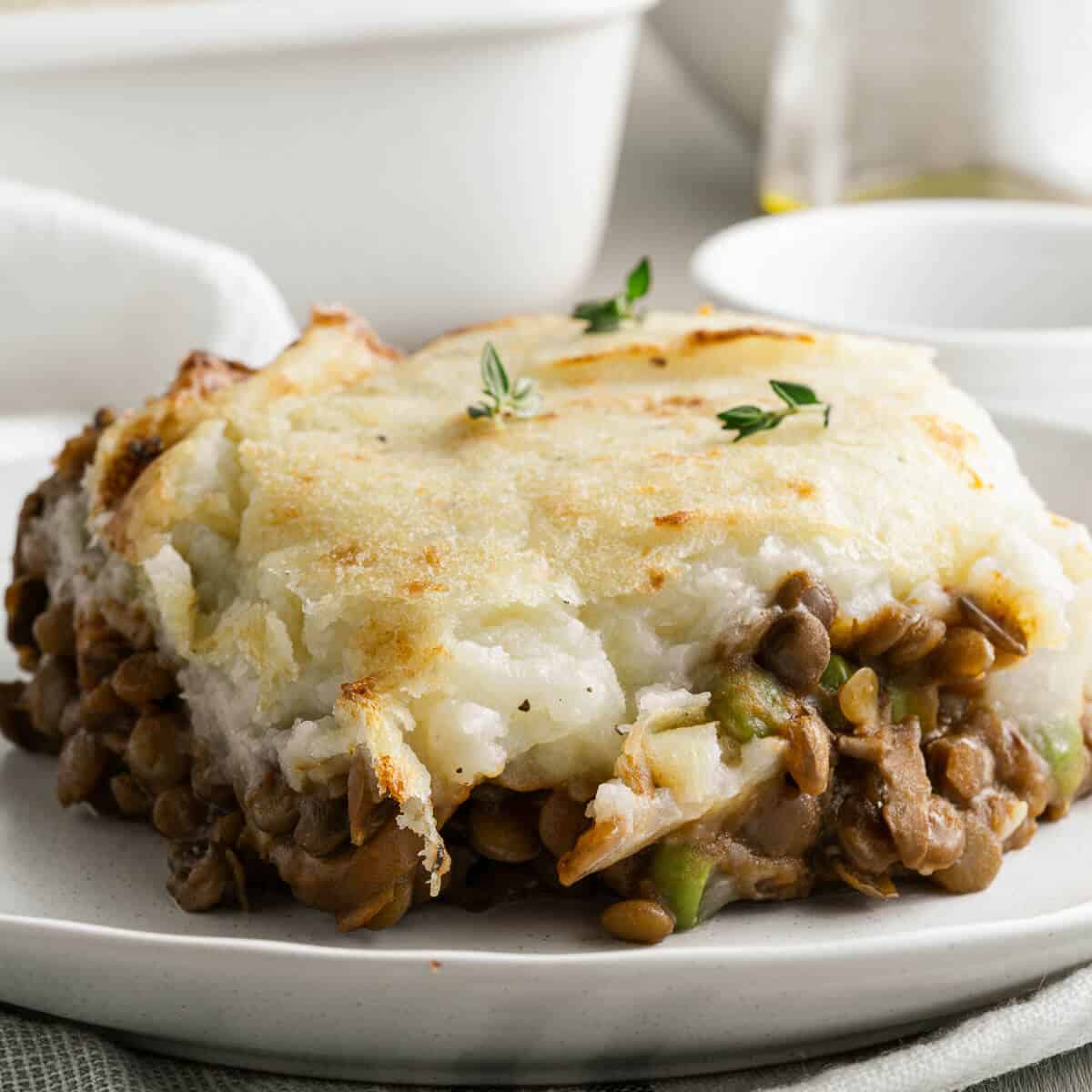 a slice of lentil shepherds pie on a white plate