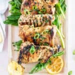 grilled chicken thighs with lemon slices that have been marinated on a serving platter