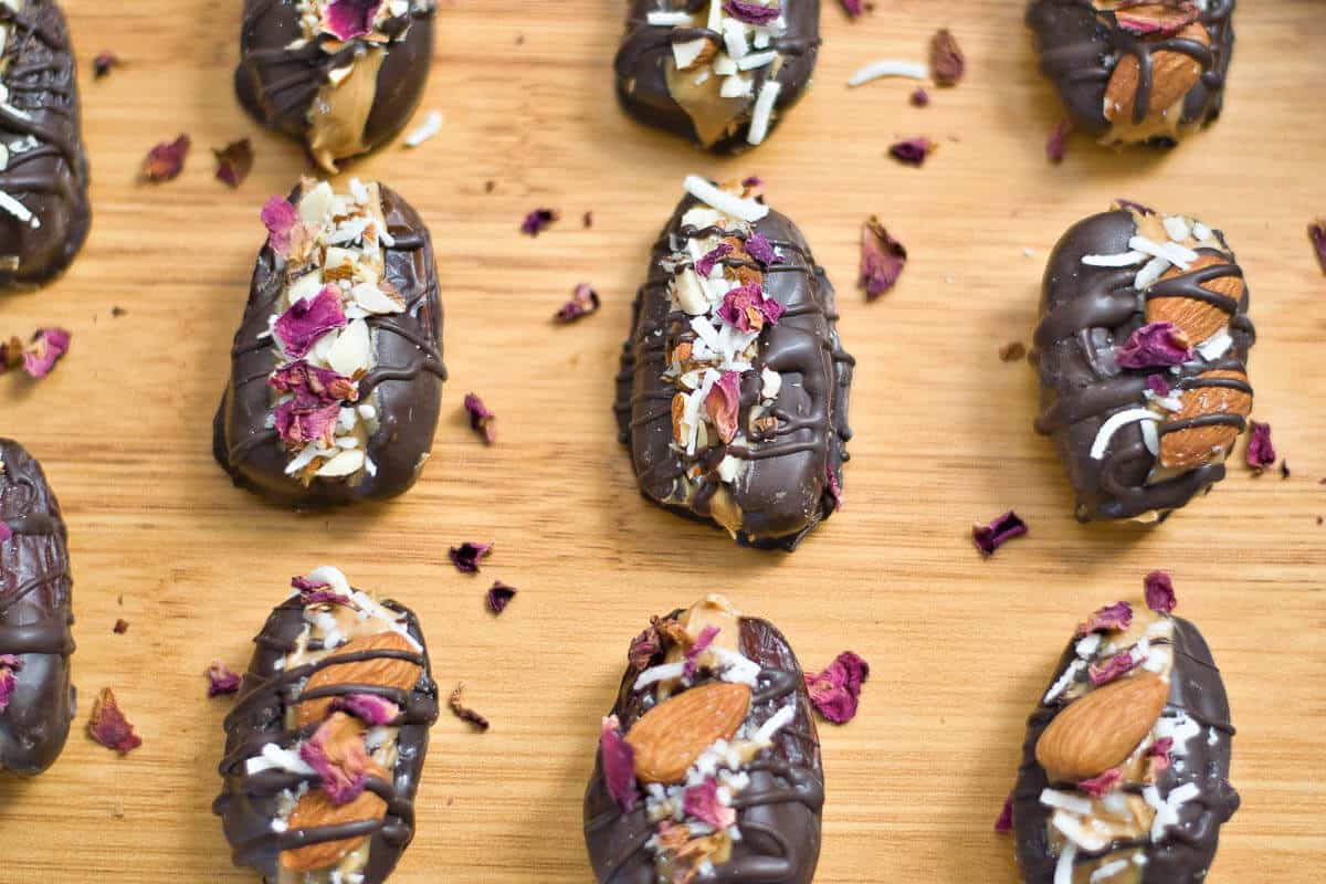 chocolate covered dates with dried rose petals on a board