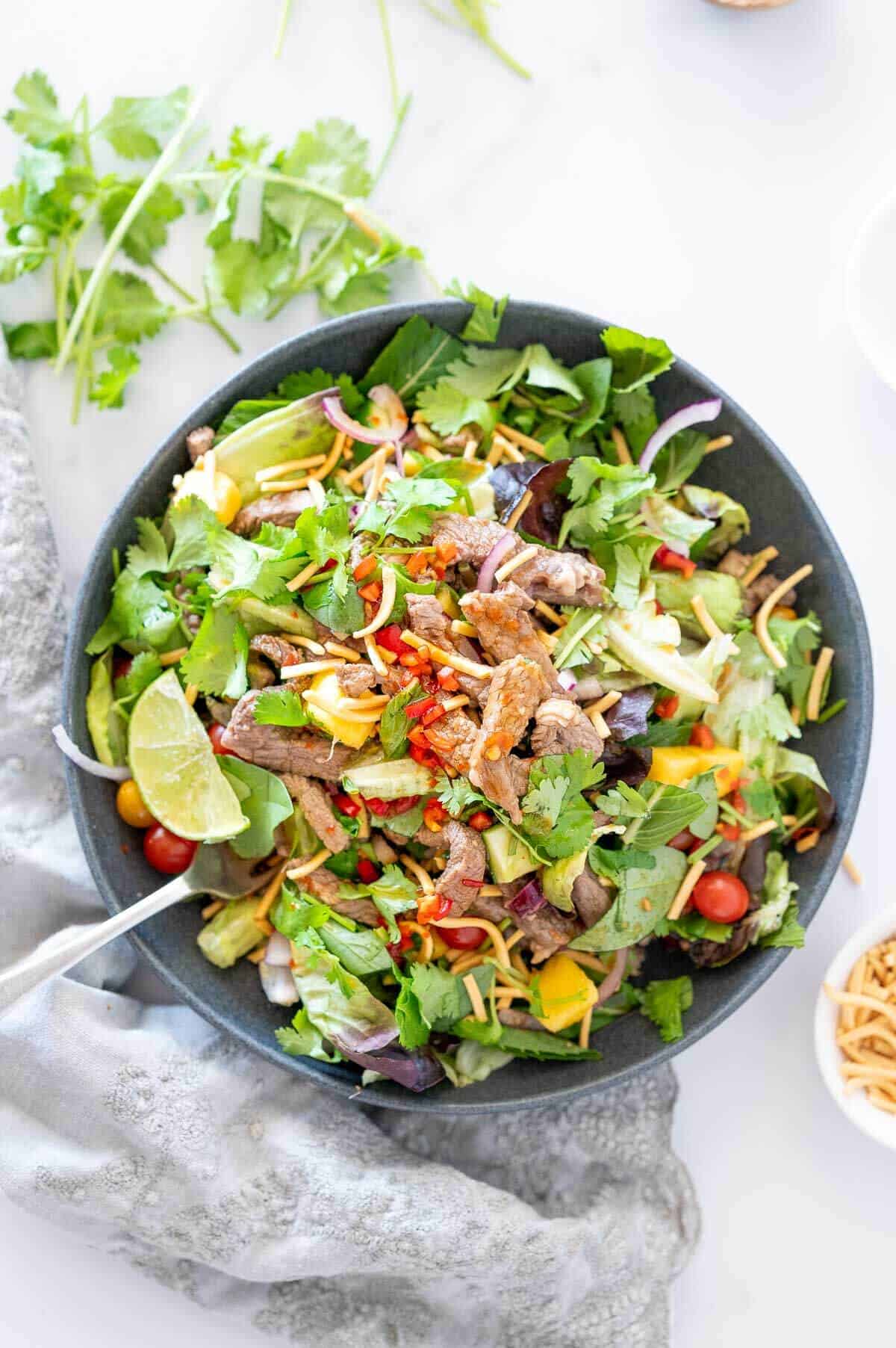 thai beef salad in a bowl with mango chunks