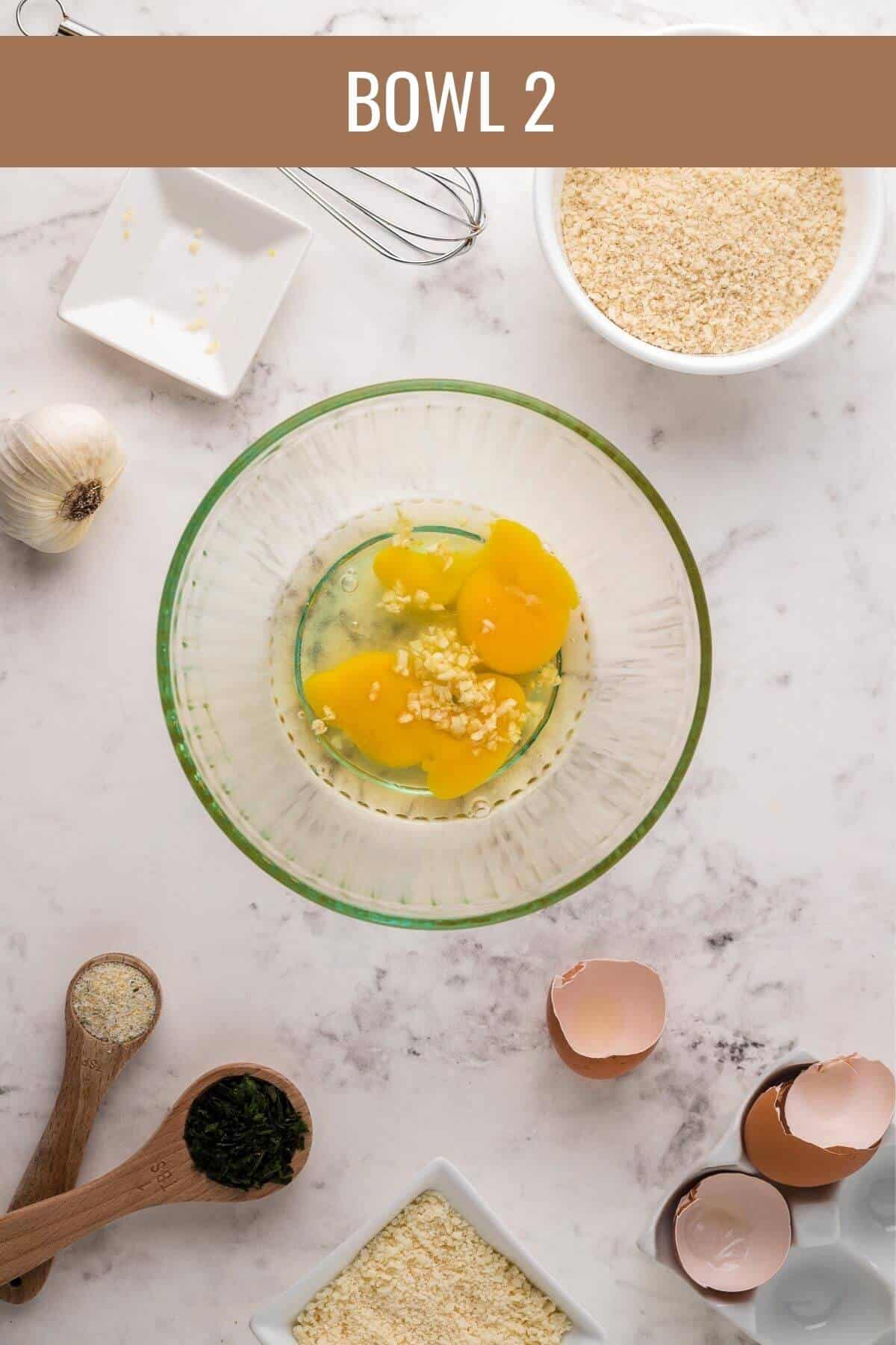 glass bowl with whisked eggs and garlic