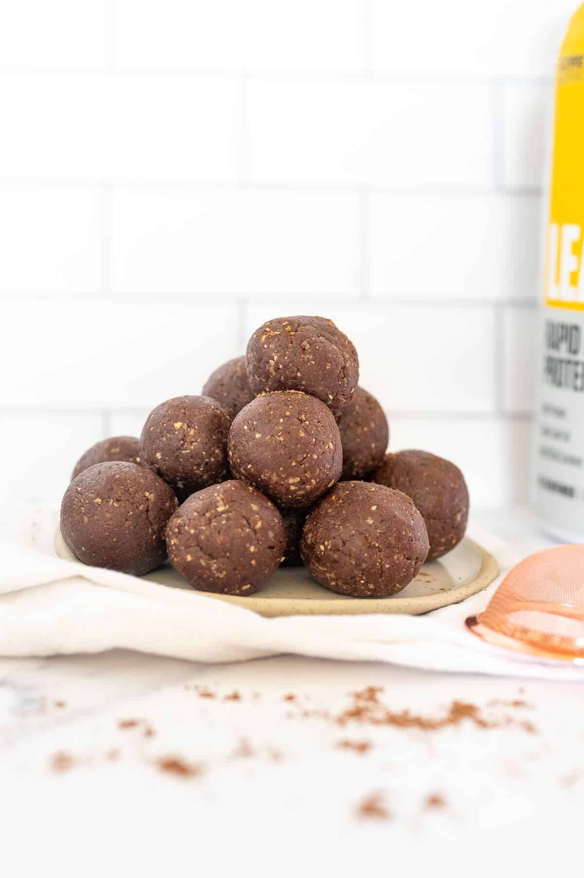 protein balls on a plate next to container of protein powder