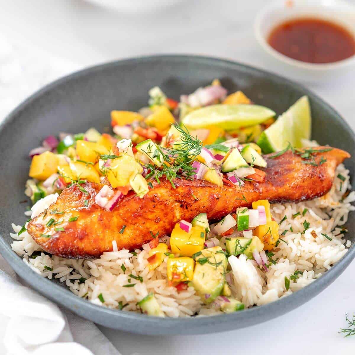 grey bowl with crispy salmon, rice and mango salsa, garnished with dill