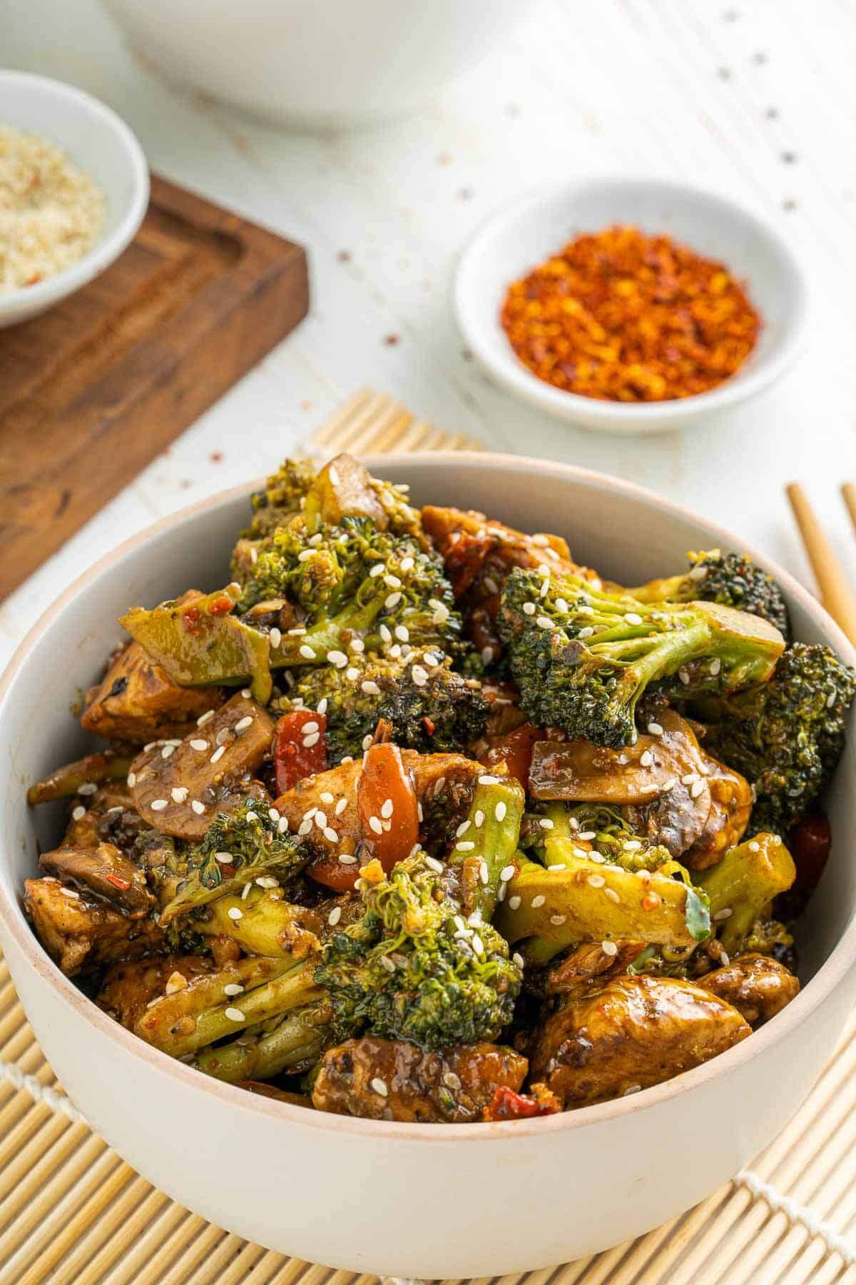 a bowl of chicken broccolli with brown sauce and sesame seeds on top