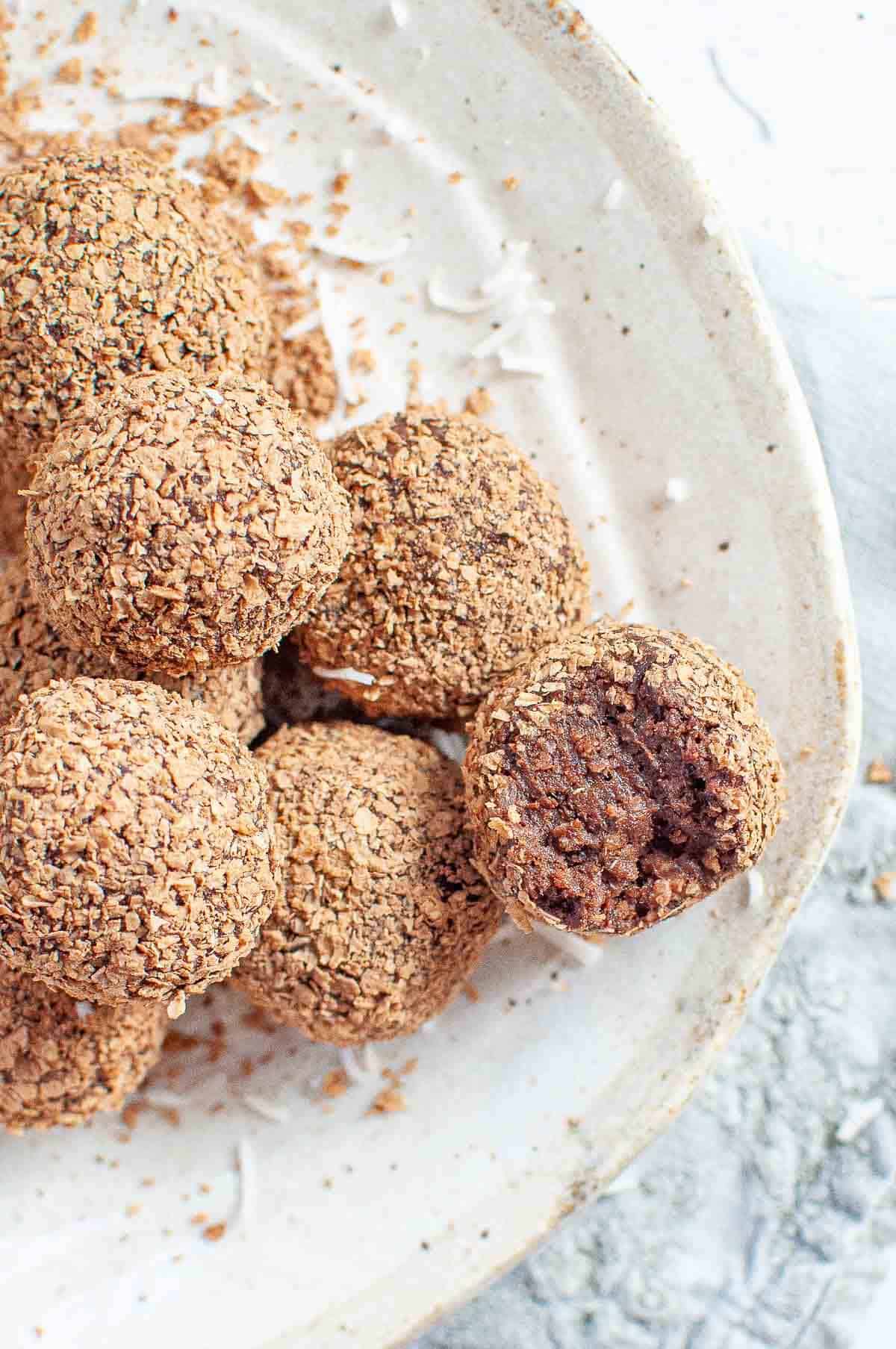 Healthy chocolate weetbix bliss balls on a white plate with bite out