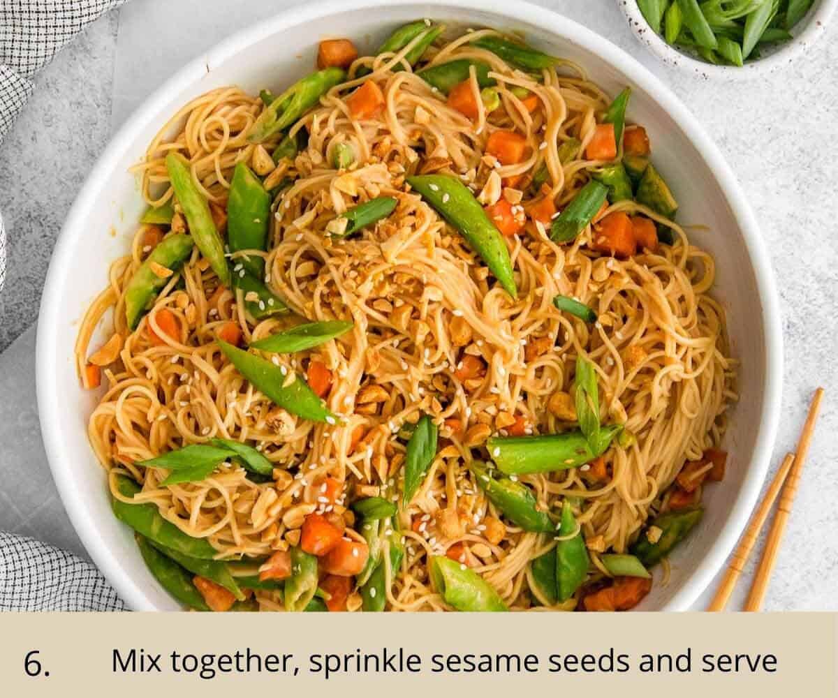 peanut noodles in a bowl with carrot, peas and sesame seeds