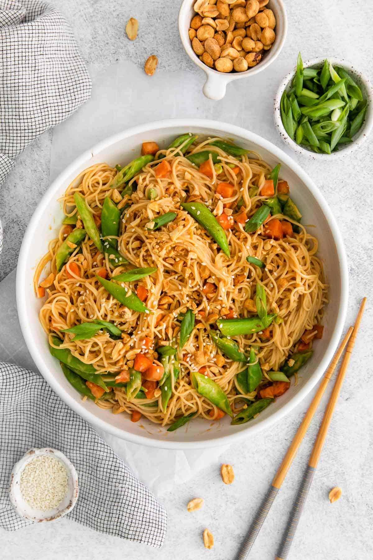 overhead photo of peanut butter sauce noodles in a bowl with chopsticks