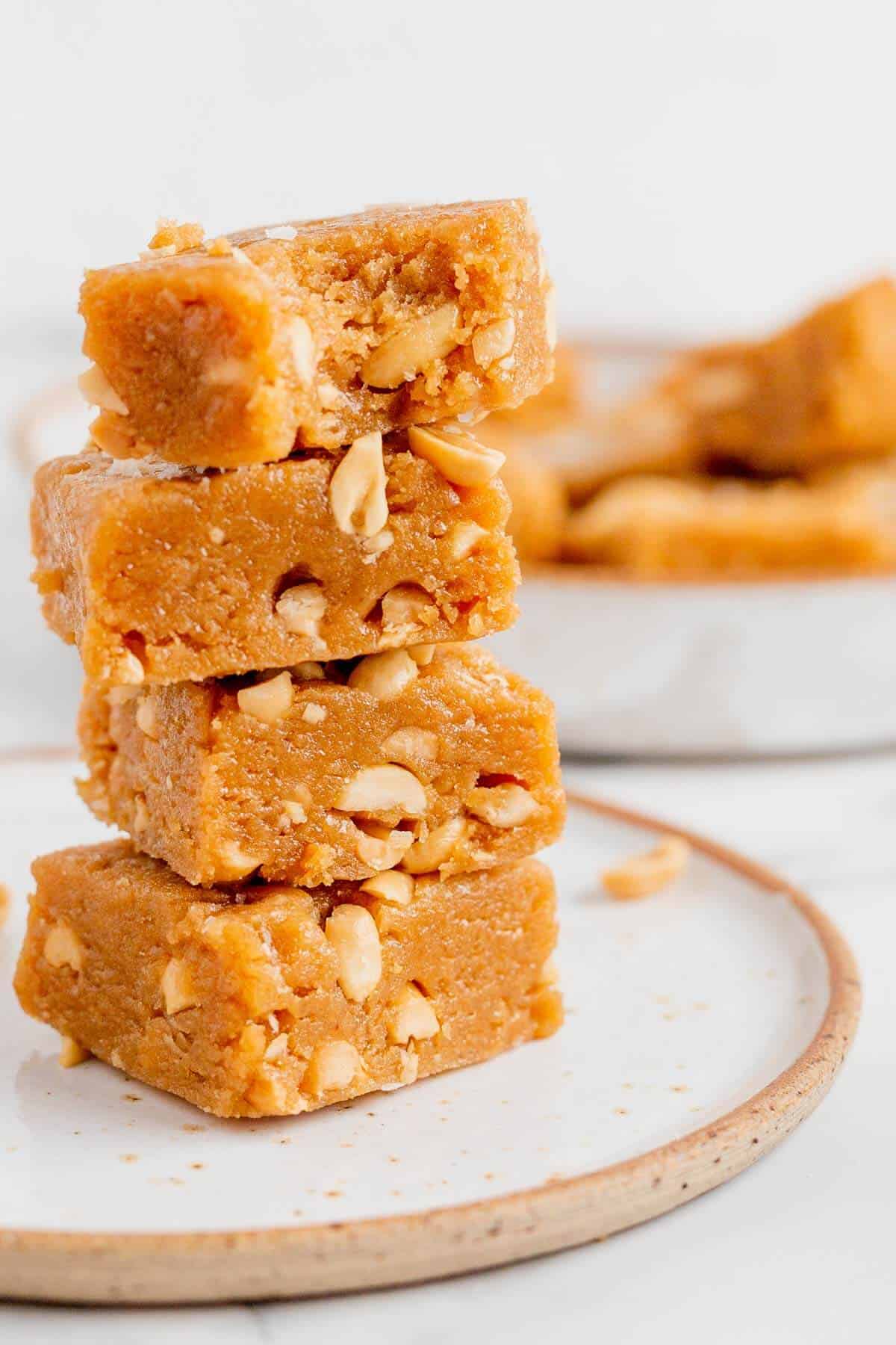 Four stacked peanut butter blondies on a plate and one with a bite out