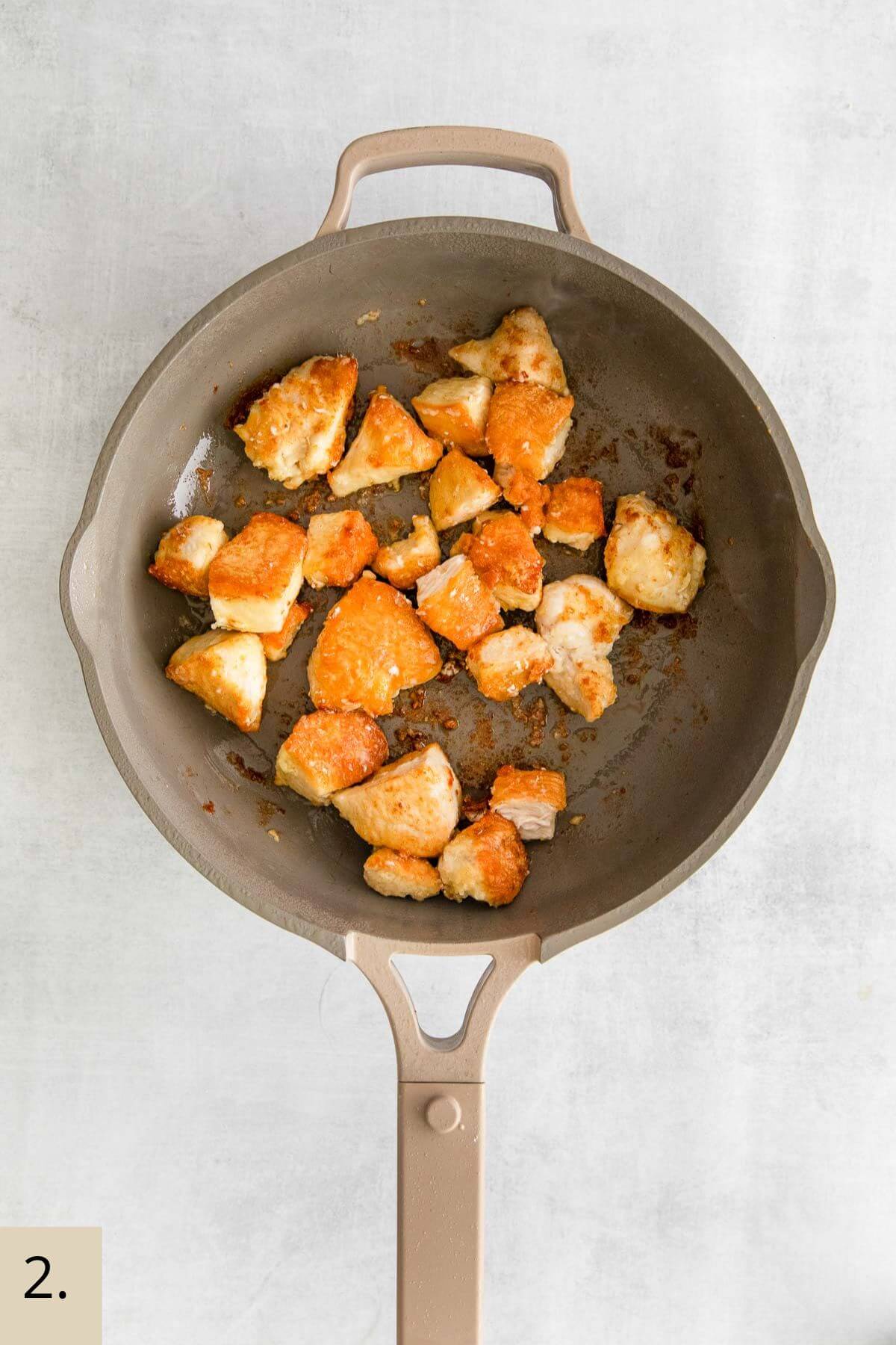 frying chicken pieces in a wok