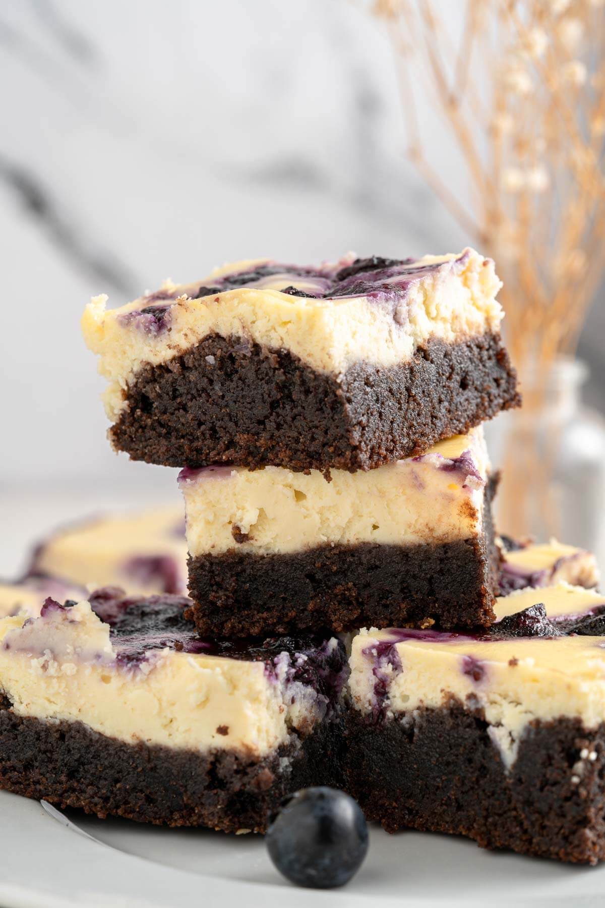 4 stacked cheesecake brownies with blueberry swirl