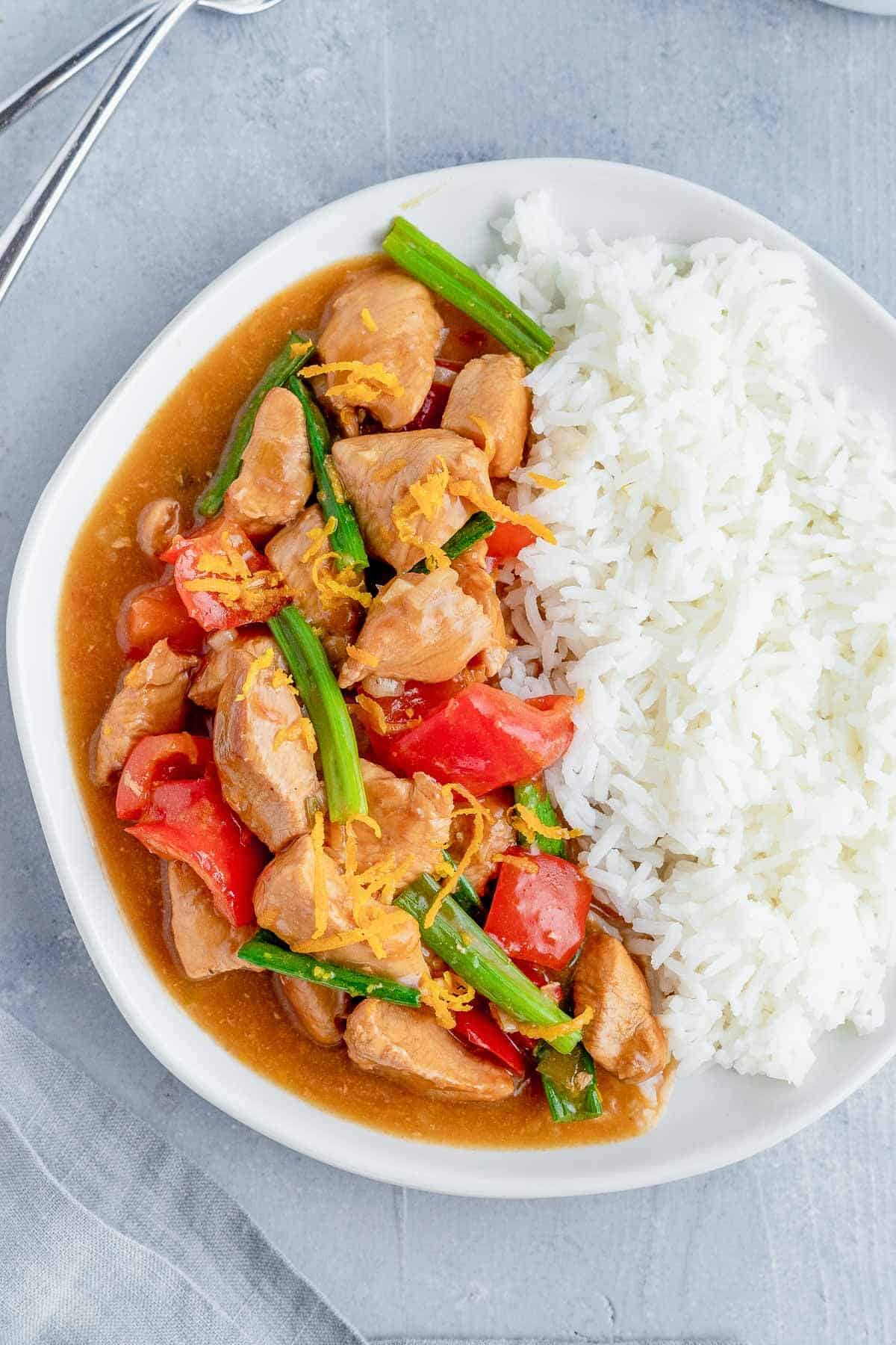 healthy chinese orange chicken with rice on a white plate