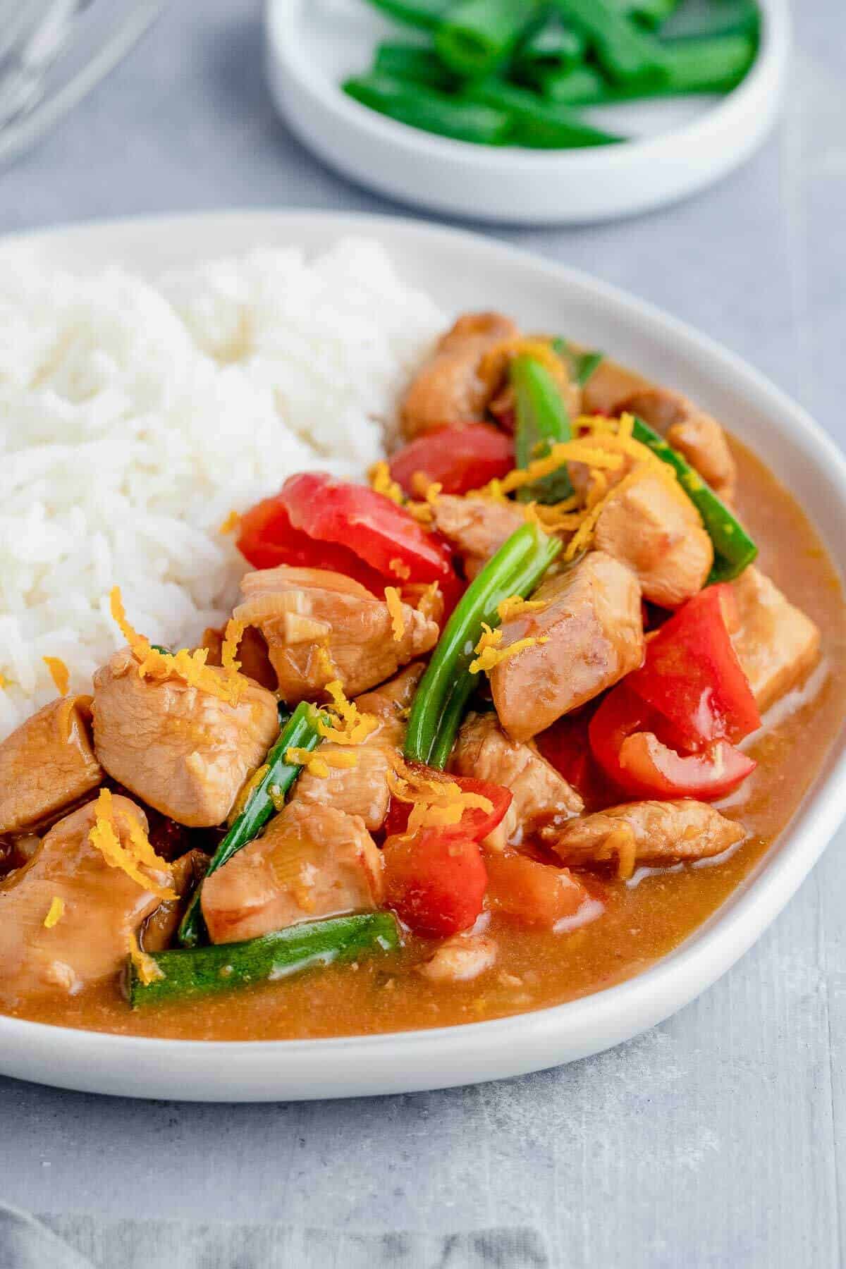 Close up of healthy orange chicken stir fry with white rice on a plate