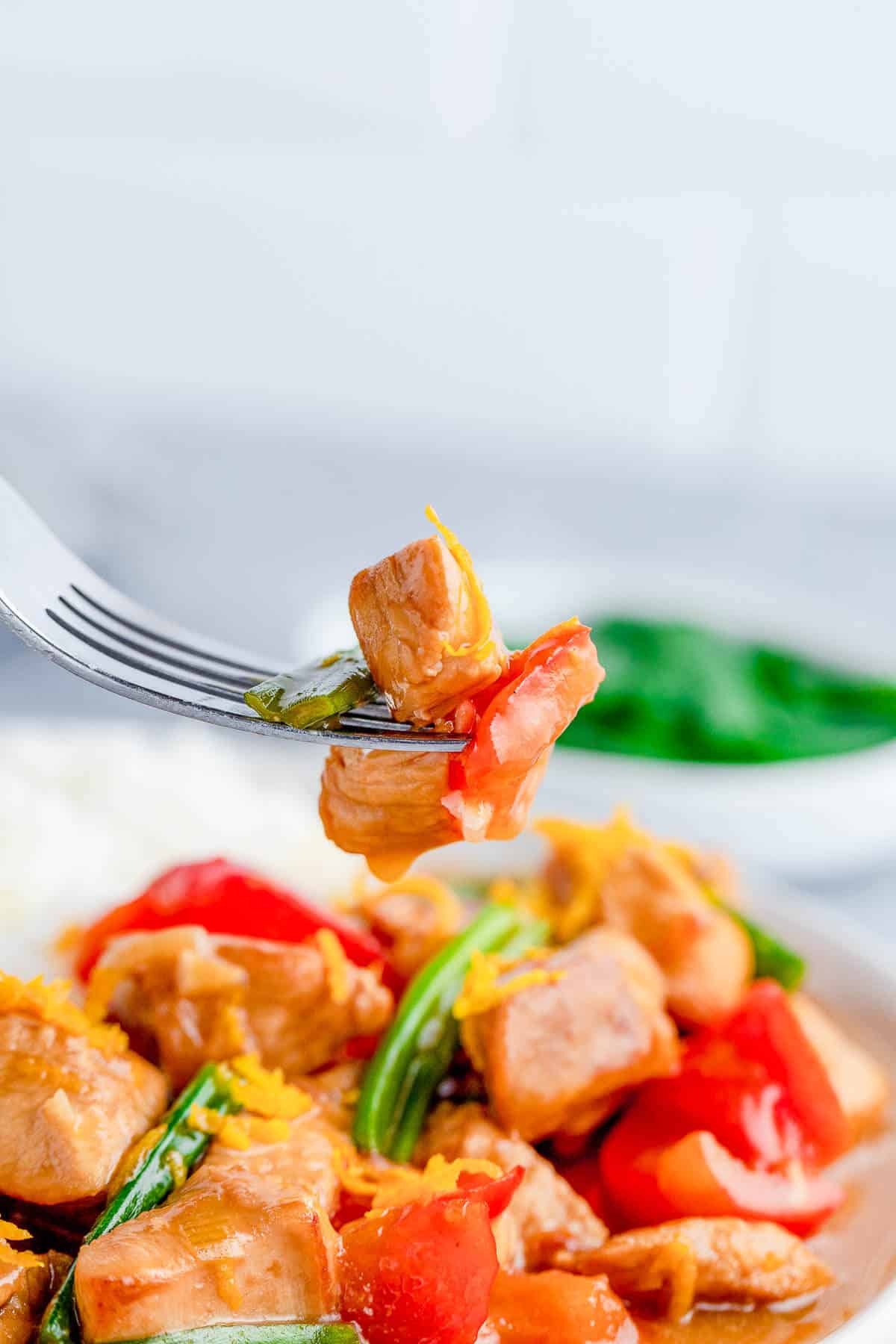 tender pieces of saucy orange chicken on a fork