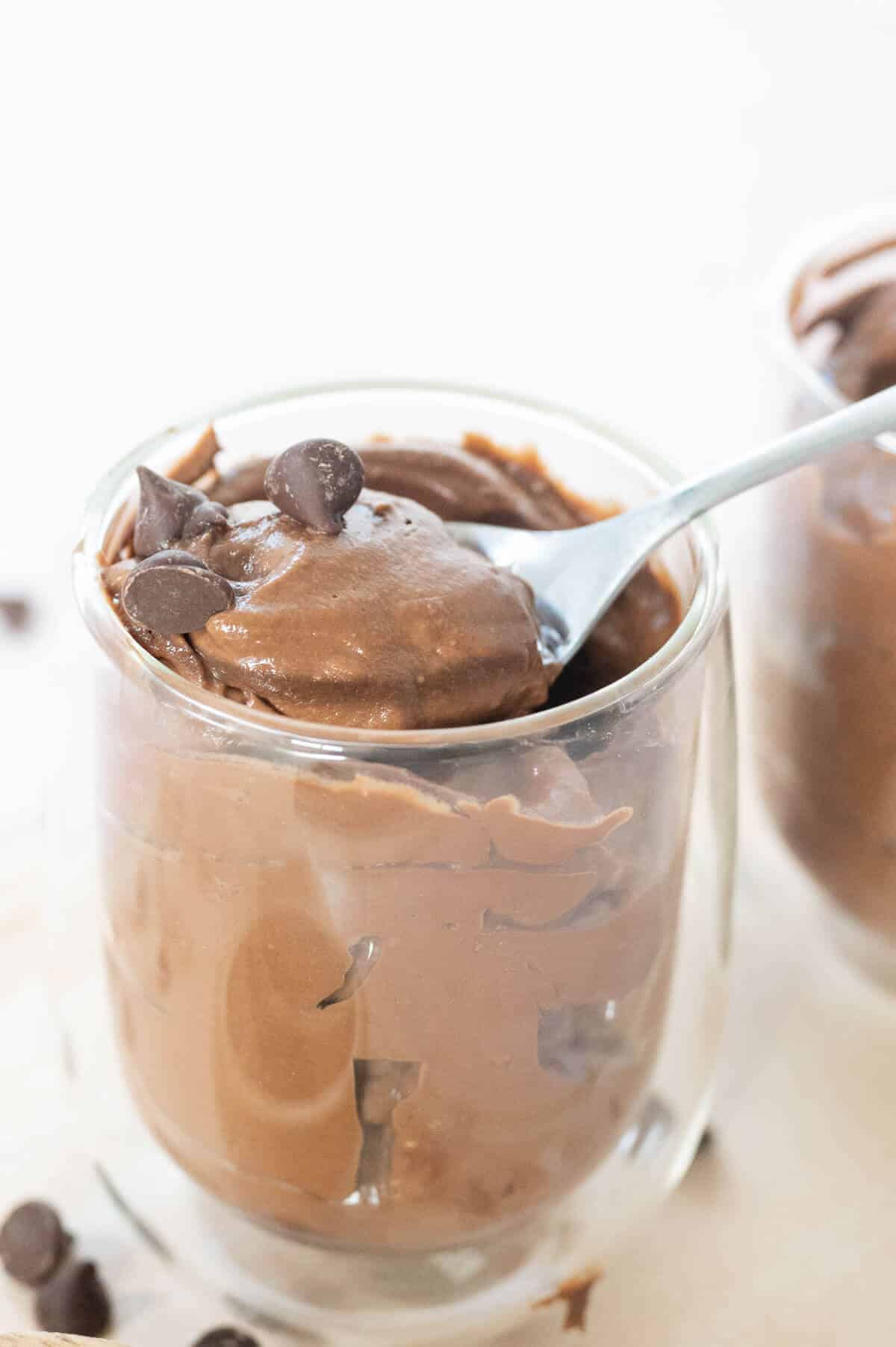 close up of chocolate cocoa avocado pudding on spoon in a jar