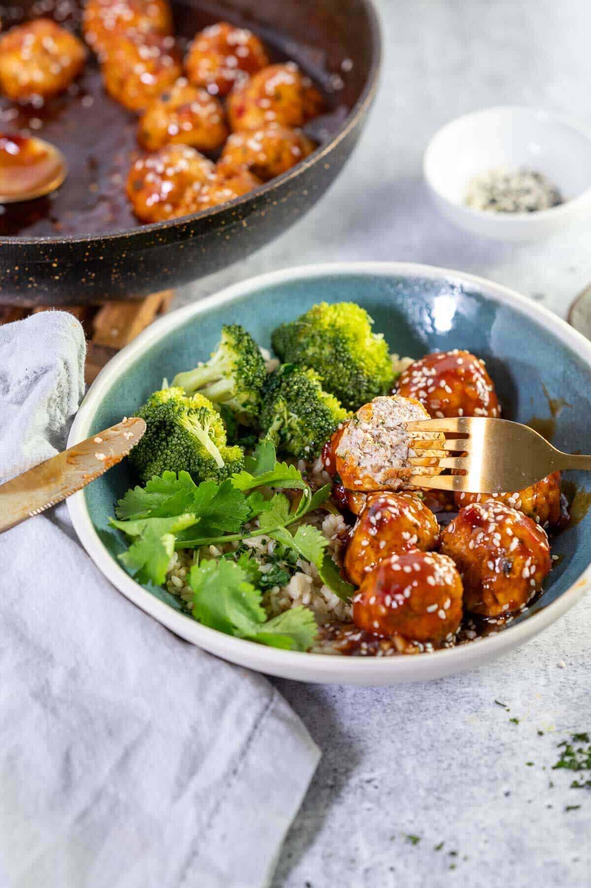 bowl of glazed meatballs with a fork stuck in
