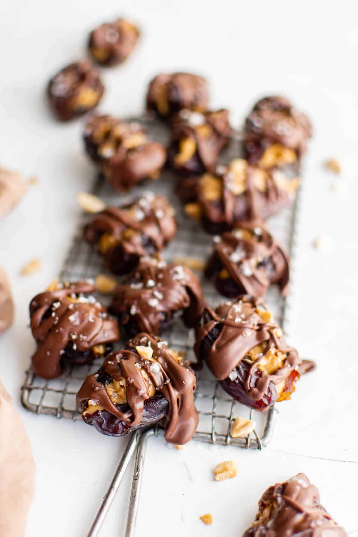 dates with peanut butter and chocolate scattered on a wire rack