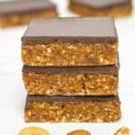 a stack of 3 date bars with nuts and chocolate on top
