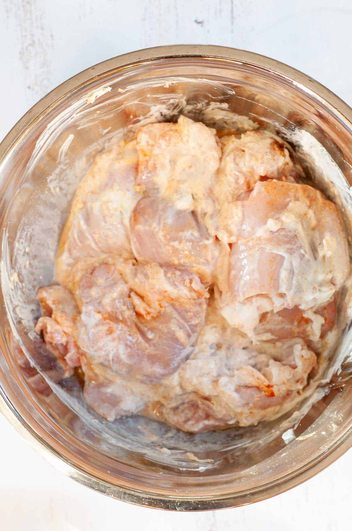 chicken thigh pieces and yoghurt marinating in a bowl