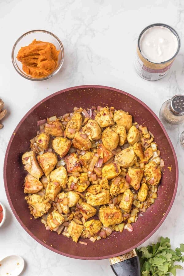 cooked chicken breast pieces and onion in a skillet