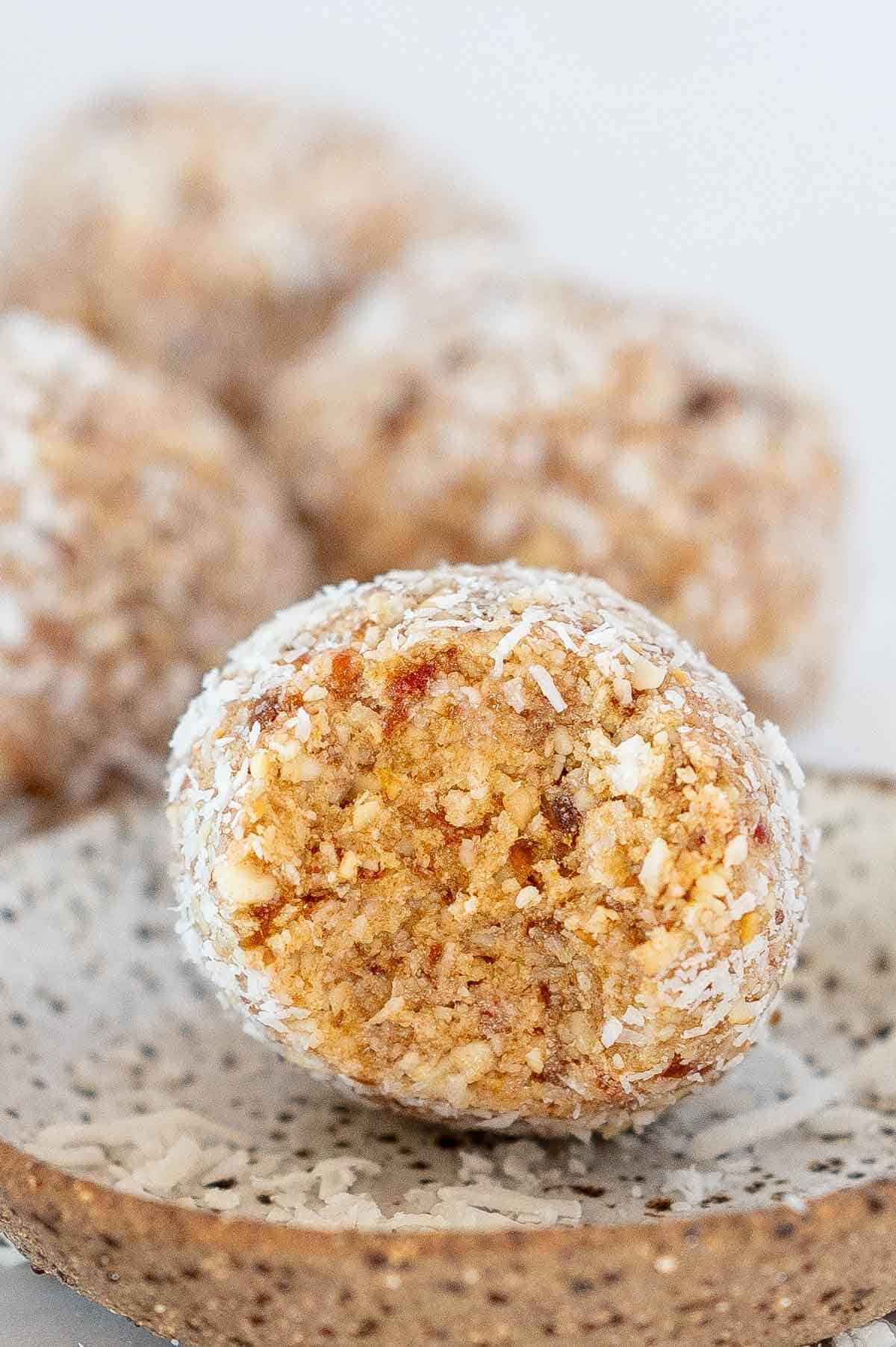 single coconut protein ball up close with a bite taken out