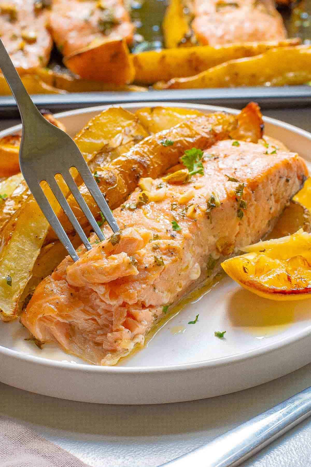 fork digging into a piece of salmon on a plate