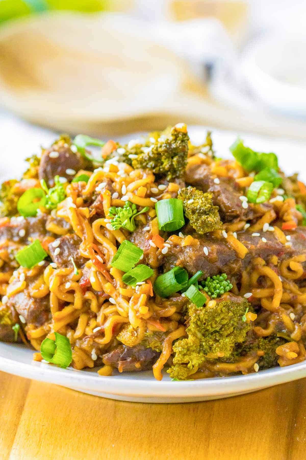noodles, steak strips, green onions and broccoli on a plate