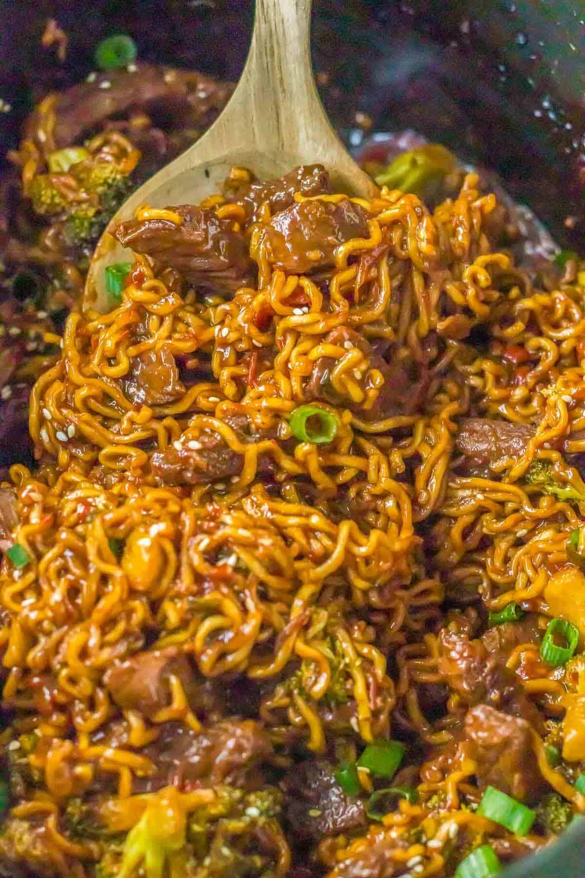 cooked beef ramen noodles on a wooden spoon in slow cooker