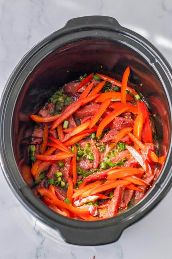 raw beef strips and bell peppers in a slow cooker