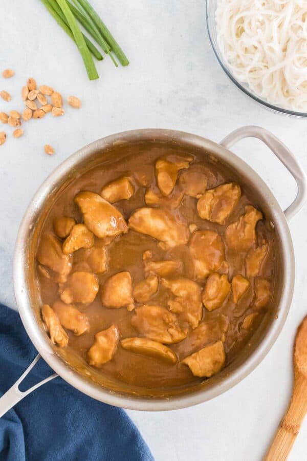 a skillet with creamy peanut butter sauce and chicken pieces