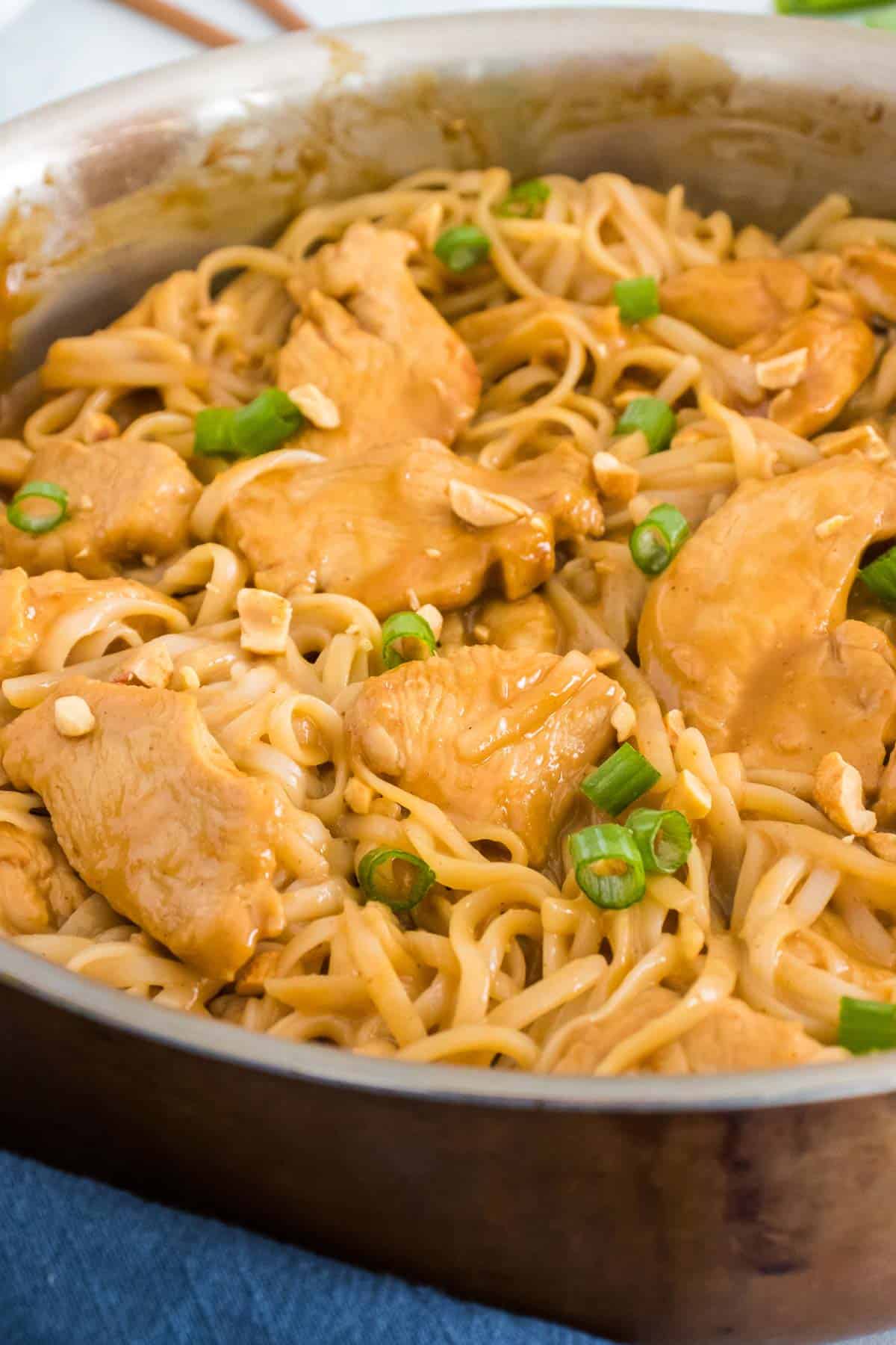 close up skillet with rice noodles, peanut sauce and chicken breast