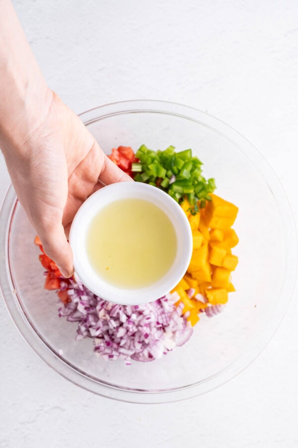 adding lime juice to a bowl of salsa