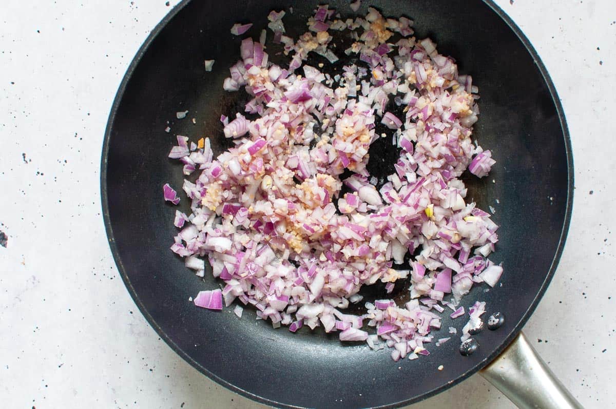 cooking red onions and garlic in a pan